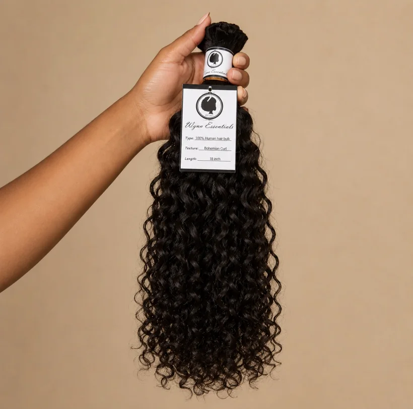 Hand holding an 18-inch Wynn Essentials Bohemian Curl human hair bulk bundle with product tag