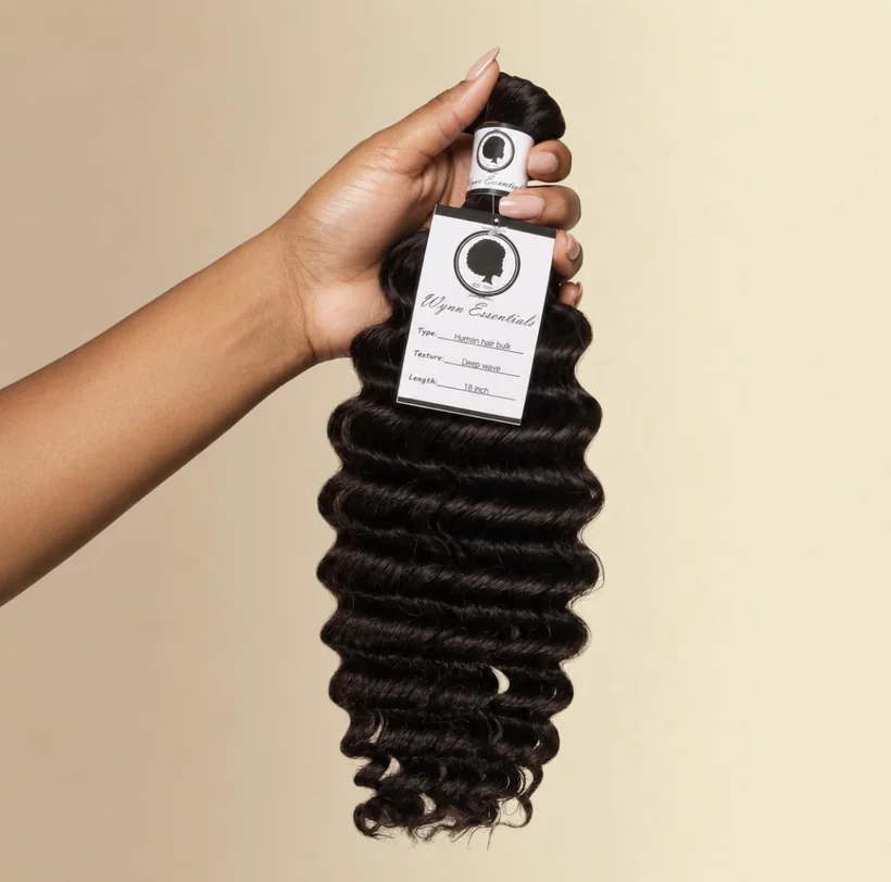 Hand holding an 18-inch Wynn Essentials Deep Wave human hair bulk bundle with product tag
