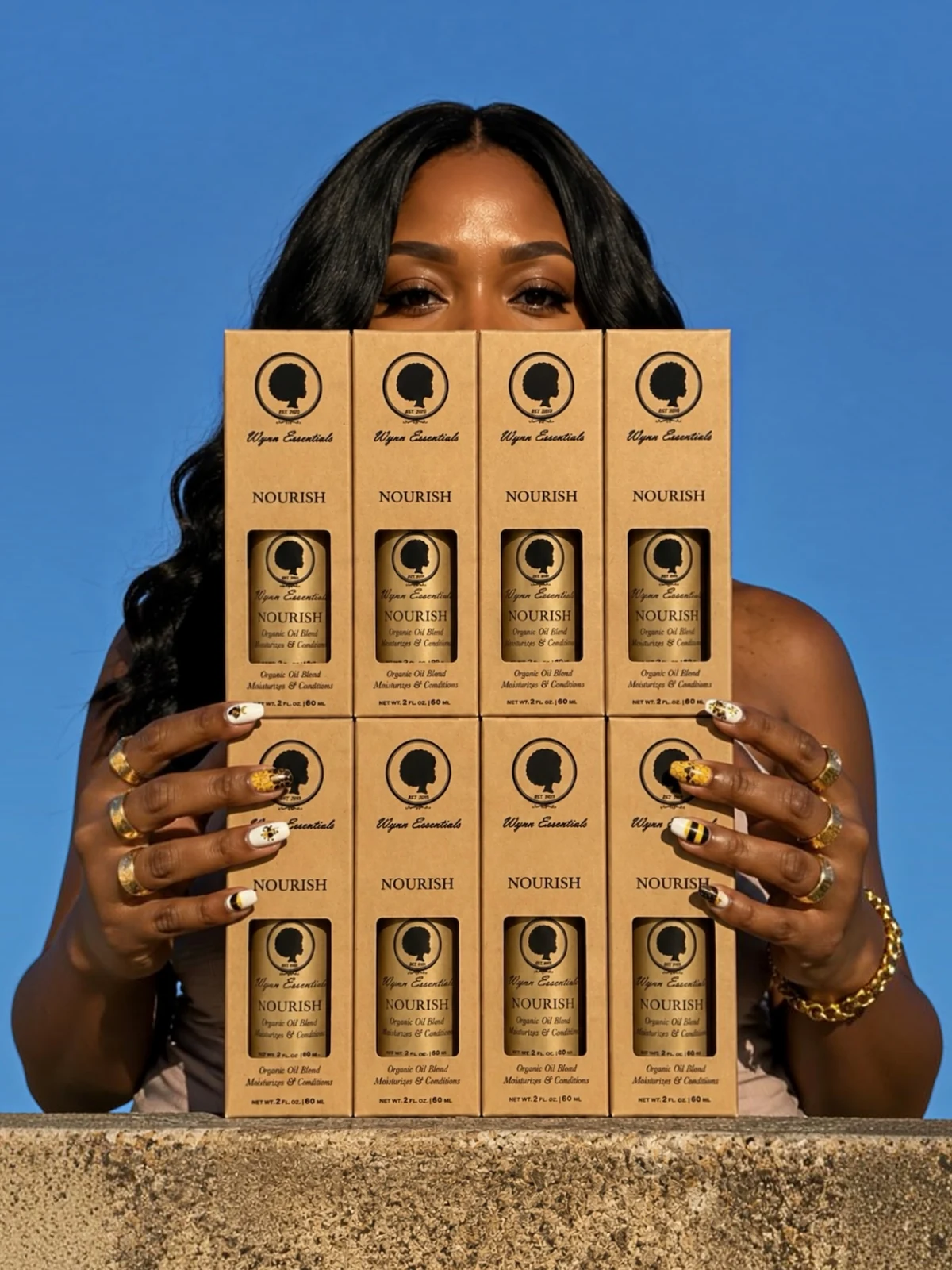 Model holding eight Wynn Essentials Nourish boxes against a bright blue sky