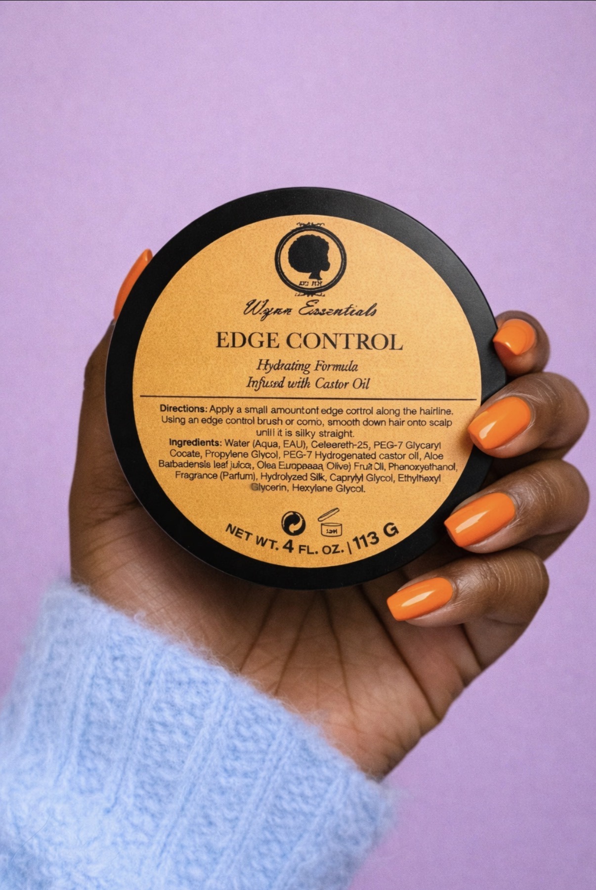 Hand holding a Wynn Essentials Edge Control jar against a lavender background