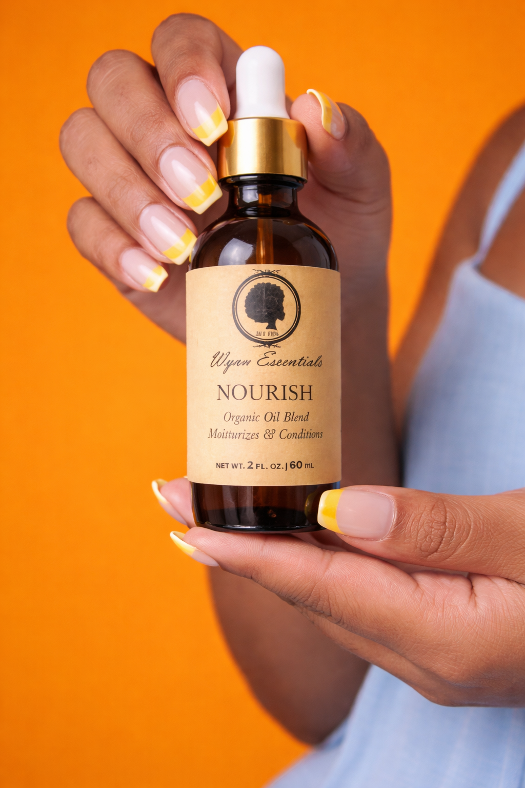 Nourish Organic Oil Blend held against a vivid orange background
